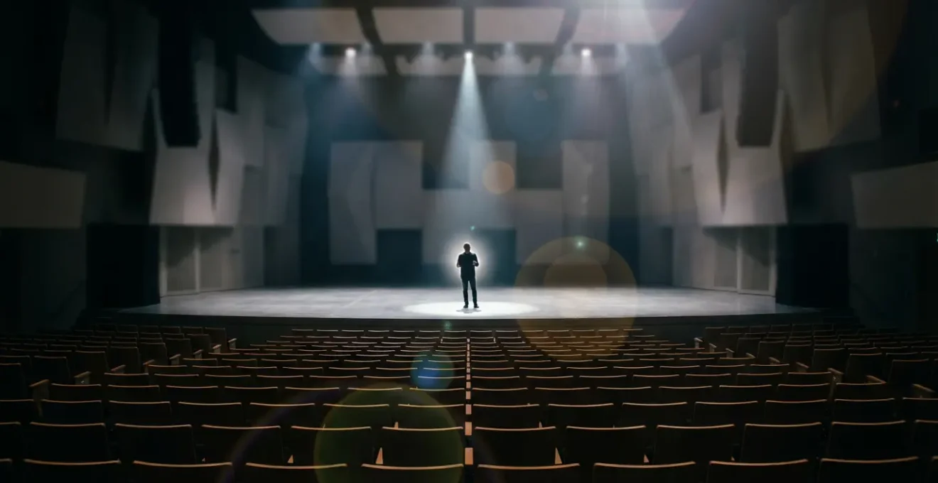 Oratore sul palco con aura luminosa espansa che riempie l'auditorium